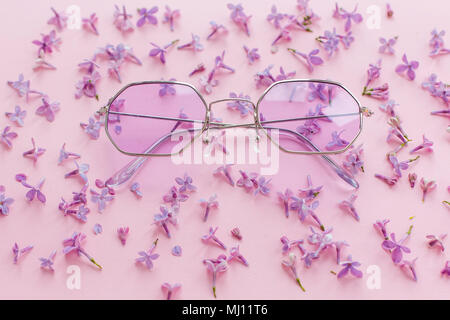 summer vacation and festival concept. stylish purple boho sunglasses on pink background with lilac flowers. creative trendy flat lay with space for te Stock Photo