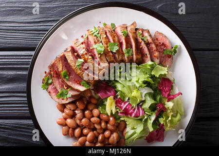Grilled Carne Asada steak with salad and beans close-up on a plate. Horizontal top view from above Stock Photo