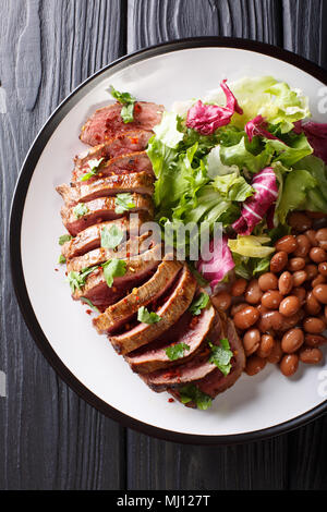 Grilled Carne Asada steak with salad and beans close-up on a plate. Vertical top view from above Stock Photo