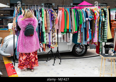 Old vintage womens clothing for sale on a rack at a retro vintage car boot sale. Granary Square, Kings Cross, London Stock Photo