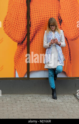 A young business woman in the city on the street reads messages on the phone. Stock Photo