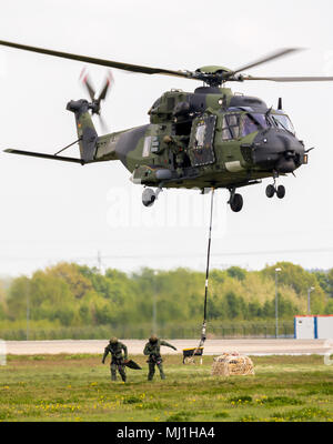 BERLIN - APR 27, 2018: German army NH-90 TTH helicopter picking up a slingload while performing at the Berlin ILA Air Show. Stock Photo