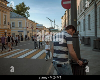 MOSCOW, RUSSIA - MAY 9, 2016: A man in a striped polo puts out a cigarette on the edge of an urn around Bolshaya Ordynka Street after the march Immort Stock Photo