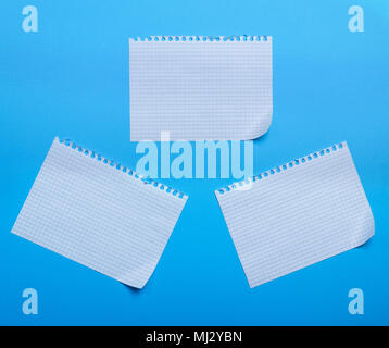 three blank sheet of paper with curved corners on a blue background, the sheets into the cell and taken out from a notebook Stock Photo