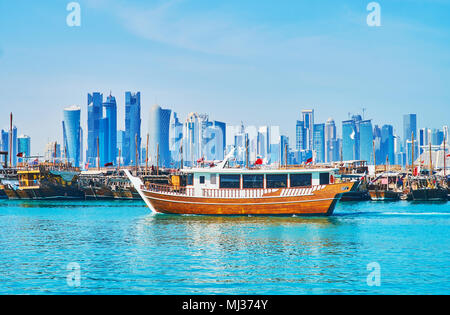 The contrast of glass futuristic skyscrapers on the coast of West Bay and traditional wooden dhow boats, moored in harbor, Doha, Qatar. Stock Photo