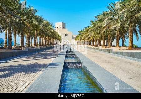 DOHA, QATAR - FEBRUARY 13, 2018: The walk along the rows of palm trees to the Museum of Islamic Art, located at the end of Corniche seaside promenade  Stock Photo