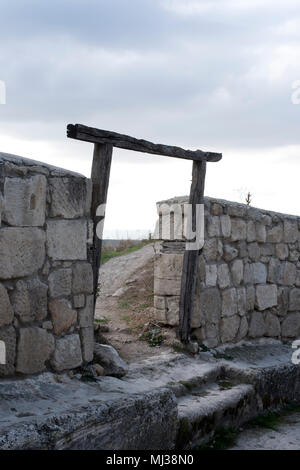 on the destroyed wall there is an arch of an old door with a footpath Stock Photo