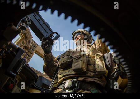 A U.S. soldier, assigned to the 2nd Battalion, 4th Infantry regiment, scans his sector of fire from atop a military fighting vehicle while escorting British forces to a bridge being built in Mosul, Iraq, March 21, 2018. The United Kingdom Bridge Training Team advises and assists Iraqi security forces in construction of an Acrow Poseidon bridge over the Tigris River. This effort is part of Combined Joint Task Force – Operation Inherent Resolve,the global Coalition to defeat ISIS in Iraq and Syria. (U.S. Army Image collection celebrating the bravery dedication commitment and sacrifice of U.S. Ar Stock Photo
