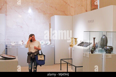 03 May 2018, Latvia, Riga: A visitor examines various items at the art museum of Riga's stock exchange. The exhibition showcasing art nouveau items will run until 5 August and present around 200 pieces from the art historical period around 1900. Photo: Alexander Welscher/dpa Stock Photo