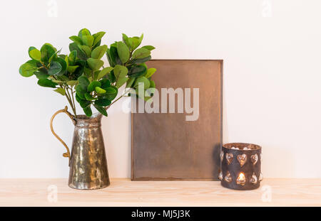 Vintage style home decor composition. Metal frame with copy space, ficus in antique jar and candle. Stock Photo