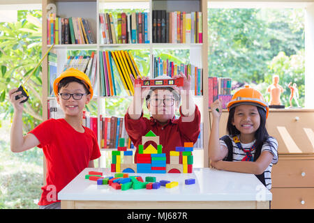 Asian kids boy and  girl holding device with plastic blocks on table Stock Photo