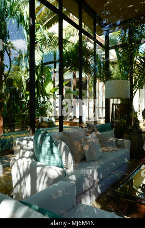 chairs and table by swimming pool against trees seen through window Stock Photo