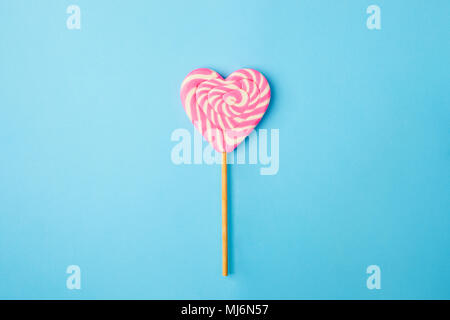 a pink and white spiral heart lollipop on blue background, flat lay minimal concept, trendy pop art style photo, isolated Stock Photo