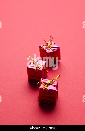 Small Red Christmas Gift Boxes organized in a row over red background with space for text or other desings Stock Photo