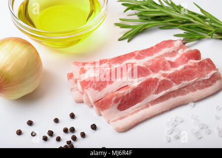 Raw bacon slices with condiments on white background Stock Photo