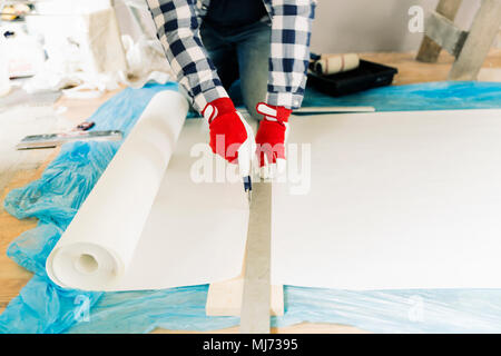 Handyman, worker measuring wallpaper to cut. Home renovation and repair concept Stock Photo