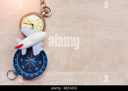 Travel and vacation plan background. Small airplane toy with pocket watch and compass on wood table. Vintage and retro filtered. Picture for add text  Stock Photo