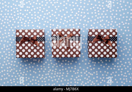 Christmas Gift Boxes with snow confetti in a row over blue background, above view Stock Photo