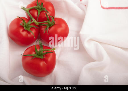 Branch with the ripe red tomatoes, and one tomato on fabric cloth with copy space high angle view Stock Photo