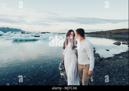 Young stylish  couple in love in Iceland. Woman and man embrace and want to kiss each other. Lovely couple kissing in glacier lagoon in Iceland. Stock Photo