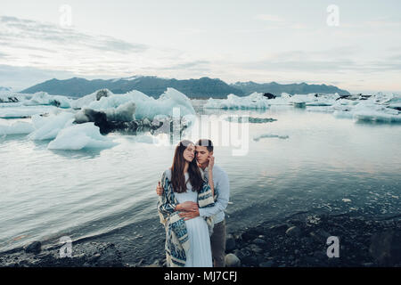 Young stylish  couple in love in Iceland. Woman and man embrace and want to kiss each other. Lovely couple kissing in glacier lagoon in Iceland. Stock Photo