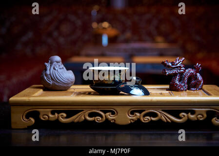 Beautiful dishes for a tea ceremony close-up on a wooden board with statues on the background of a blurred living room. Stock Photo
