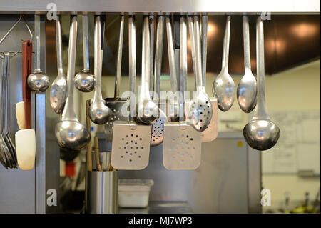 Cooking utensils hanging up in a kitchen in a large restaurant Stock Photo