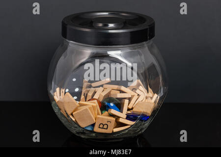 a jar full of word tiles dice marbles and colorful stones Stock Photo