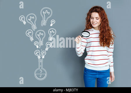 Cheerful student holding a magnifying glass and smiling Stock Photo