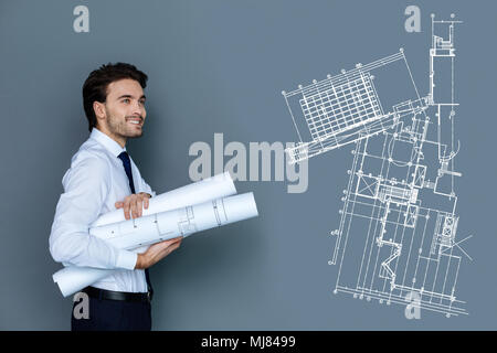 Happy young engineer smiling while carrying graphics to his colleagues Stock Photo