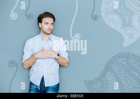 Waist up of serious puzzled man keeping fingers crossed Stock Photo