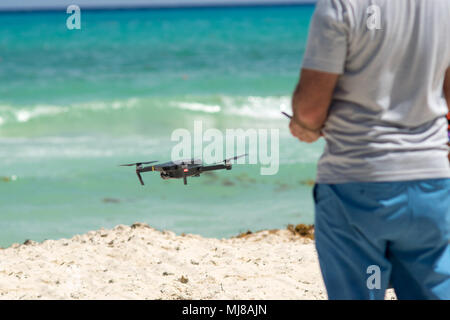 Man pilot controls the drone at beach Stock Photo