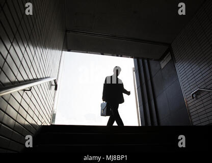 Low angle view of man carrying briefcase entering entrance to subway station. Stock Photo