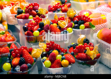 High angle close up of plastic punnets with a selection of summer fruits including strawberries, redcurrants, blueberries and grapes. Stock Photo