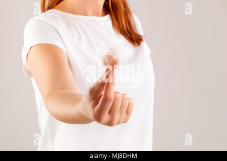 Women's Hair Loss. Beautiful redhair with hair tuft in hand isolated. Stock Photo