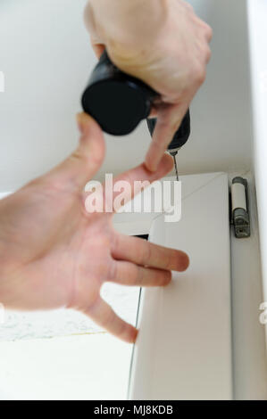 Male is drilling a hole in the window frame. Stock Photo