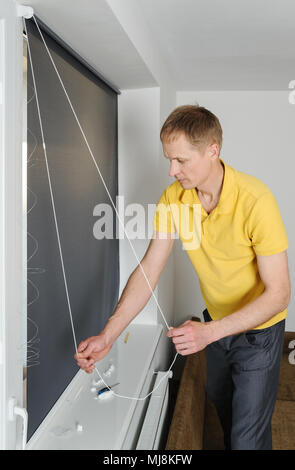 Man is holding a chain for roller blind. Stock Photo