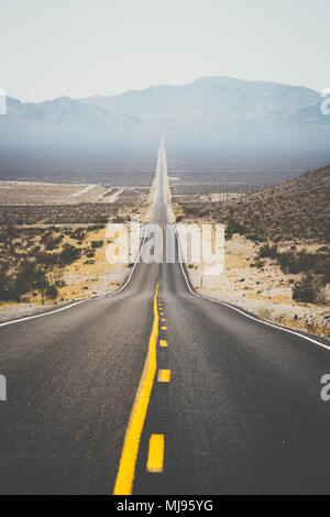 Classic panorama view of an endless straight road running through the barren scenery of the American Southwest Stock Photo