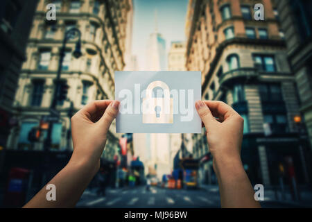 Woman hands holding a paper sheet with lock symbol in the middle of the street in a big city. Padlock as security symbol in business. Data privacy pro Stock Photo