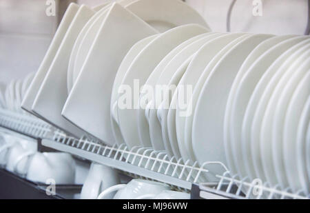 Different white clean plates and cups dry on a shelf close-up Stock Photo