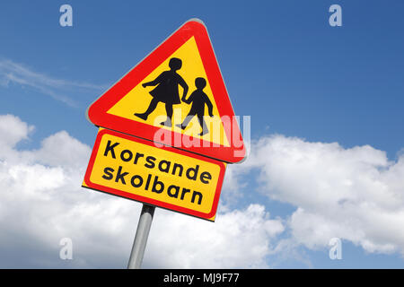 Swedish road sign, warning for children with additional sign with the text, intersecting school children, isolate on blue sky with clouds. Stock Photo