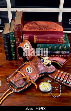 Old cowboy gun in holster with pocket watch and literature. Stock Photo