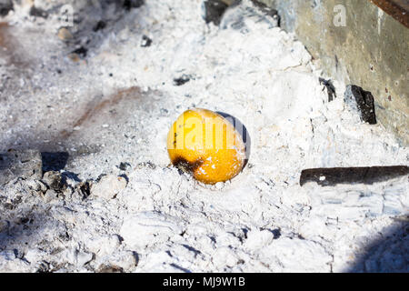 A lemon left burning inside the charcoal tray of a barbecue. Stock Photo