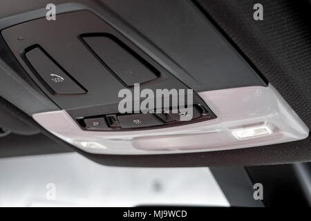 Close-up, isolated view of an emergency SOS call button together with lighting buttons seen in the roofline of a luxury, german-made sports car. Stock Photo