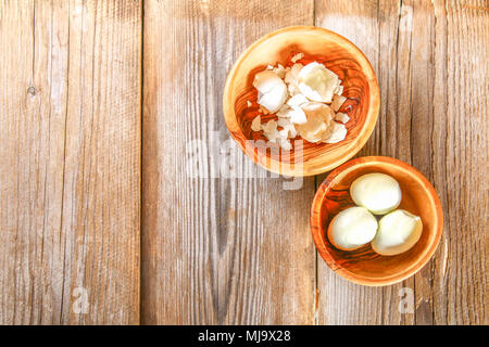 Boiled chicken eggs and their shells in wooden bowls on an old wooden table Stock Photo