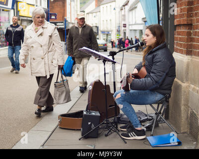 Abergavenny, Wales, UK: April 04, 2017: Busker in Abergavenny Town centre, street singer and guitar player young lady, who was singing in a public pla Stock Photo