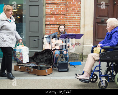 Abergavenny, Wales, UK: April 04, 2017: Busker in Abergavenny Town centre, street singer and guitar player young lady, who was singing in a public pla Stock Photo