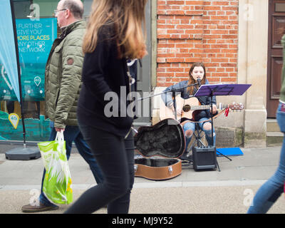 Abergavenny, Wales, UK: April 04, 2017: Busker in Abergavenny Town centre, street singer and guitar player young lady, who was singing in a public pla Stock Photo