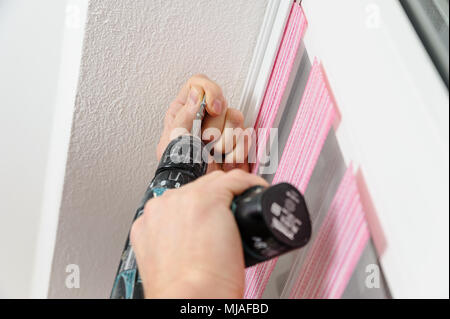 Installing fabric roller blinds. A man fixes basis blinds to frame the window. Stock Photo