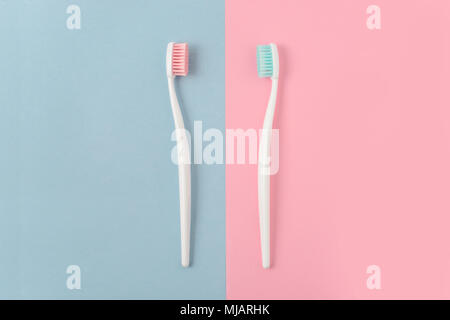 Close up of two plastic white toothbrushes with pink and blue bristle on pink and blue background. Free copy space. Stock Photo